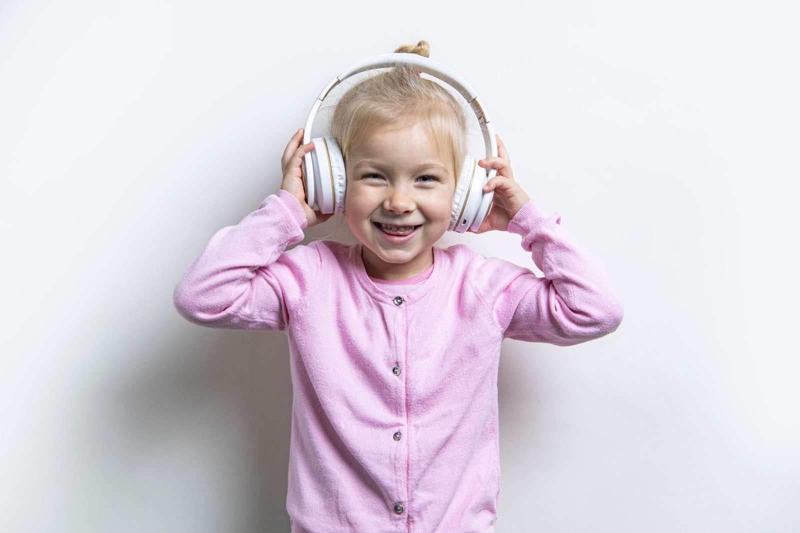 Lächelndes Mädchen mit weißen Kopfhörern auf hellem Hintergrund, Lieder auf Englisch